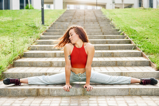 Young woman doing the splits on outdoor stairs