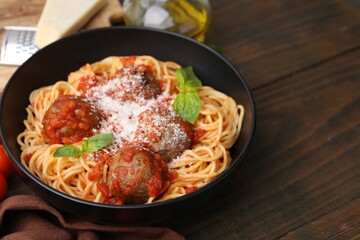 Delicious pasta with meatballs and cheese in bowl on wooden table, closeup. Space for text