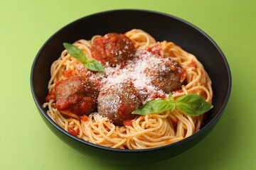 Delicious pasta with meatballs and cheese in bowl on green table, closeup