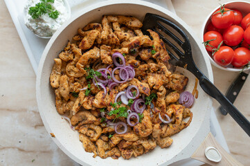 Pan fried chicken gyros fresh and homemade cooked. Made with chicken breast and served in a white frying pan.