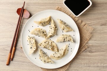 Delicious gyoza dumplings with sesame seeds served on wooden table, top view