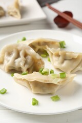 Delicious gyoza dumplings with chives served on white table, closeup