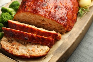 Delicious turkey meatloaf with vegetables on black table, closeup