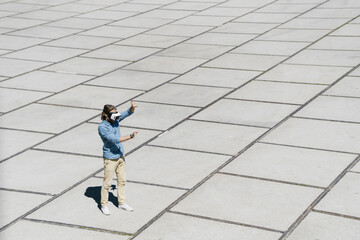 Young man with VR glasses standing on a square