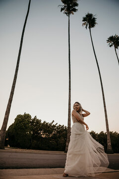 Bride standing at a road with palm trees