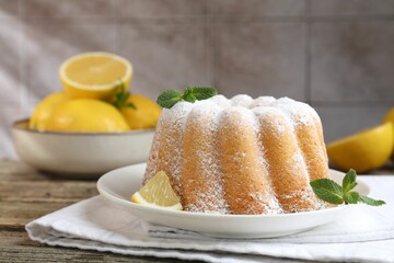 Tasty lemon cake with powdered sugar, fresh fruit slice and mint on wooden table, closeup