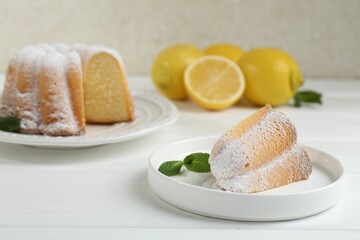 Piece of delicious lemon cake with powdered sugar and mint on white wooden table