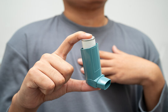 Asthma and chronic obstructive pulmonary disease COPD, Asian young man using metered dose inhaler MDI.