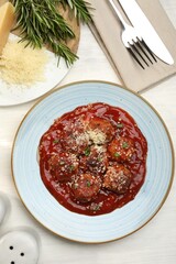 Delicious meatballs with tomato sauce, parmesan and herbs in served on white wooden table, flat lay