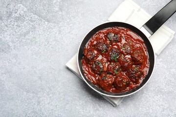 Delicious meatballs with tomato sauce and herbs in on grey table, top view. Space for text
