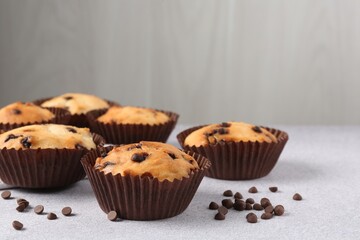 Delicious muffin with chocolate chips on light grey table, closeup