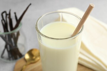 Delicious vanilla milk with bamboo straw in glass on grey table, closeup