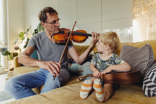Toddler watching his father playing violin