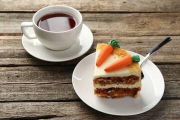 Piece of delicious homemade carrot cake and tea on wooden table