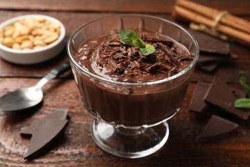 Tasty pudding with mint and pieces of chocolate served on wooden table, closeup