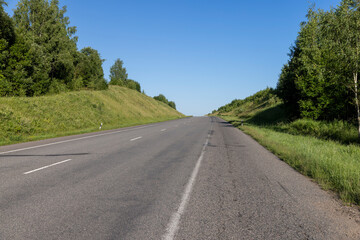 Fototapeta premium an empty straight paved road against a blue sky background