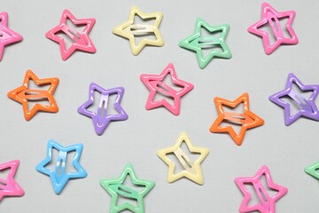 Colorful star shaped hair clips on light grey background, flat lay