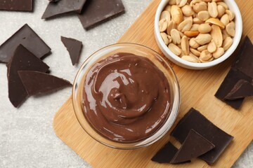 Delicious chocolate mousse in glass bowl and ingredients on grey table, flat lay