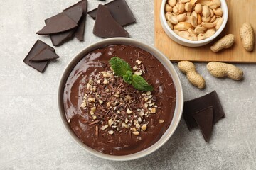 Delicious chocolate mousse in bowl and ingredients on grey table, flat lay