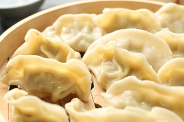 Tasty boiled gyoza (dumplings) in bamboo steamer on table, closeup