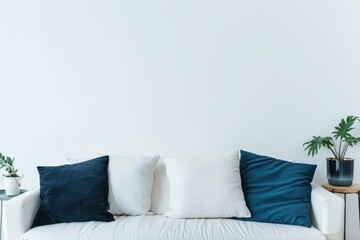 Minimalist living room with a white couch and blue throw pillows. featuring a white wall as a backdrop