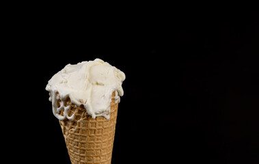 creamy ice cream in a waffle cone on a black background