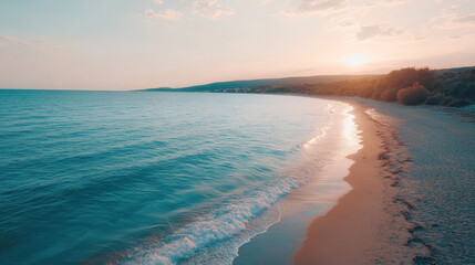 Calm ocean waves gently lap against sandy shore under glowing pink sky, creating serene atmosphere at sunset