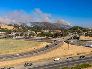 Wildfire smoke blankets hills above highway, traffic continues. Evacuations possible. Cordelia,...
