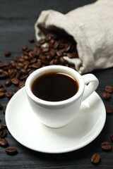 Cup of coffee with fresh coffee beans on wooden background