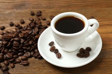 Cup of coffee with fresh coffee beans on wooden background