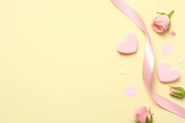 Beautiful composition with pink roses, hearts and silk ribbon on a colored background