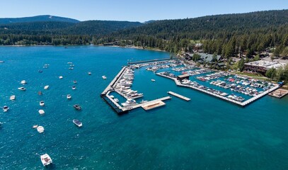 Aerial view of a bustling Lake Tahoe marina. Many boats are docked, and the surrounding area has...