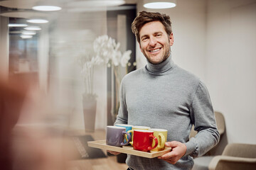 Friendly professional in a London office holding a tray of refreshments