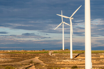 A group of wind turbines aligned in a rural landscape in Zaragoza, Spain, demonstrating large-scale renewable energy production.