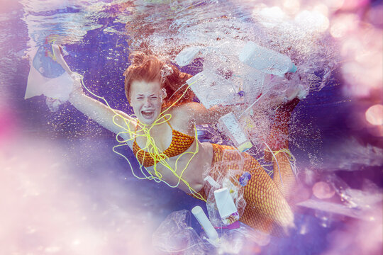 Screaming teenage mermaid girl surrounded by plastic waste under water