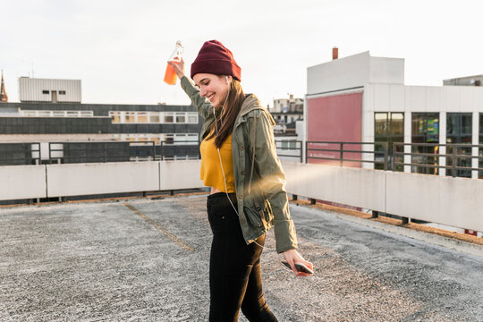 Happy young woman with earphones dancing on parking deck