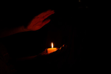 Burning candle in a man's hand in the darkness of the house, candle flame, lighting