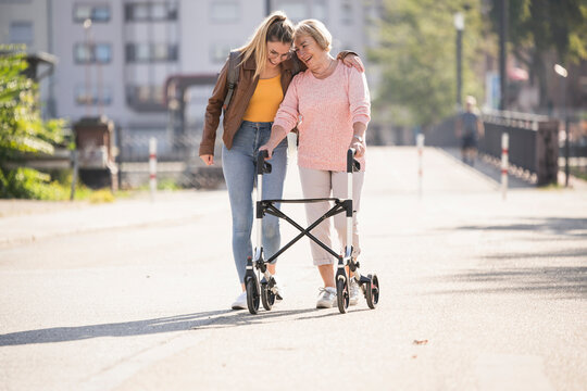 Granddaughter assisting her grandmother walking with wheeled walker