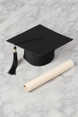 Graduation cap rests beside rolled diploma on elegant marble sur