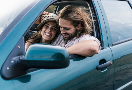 Happy couple enjoying a road trip in a car outdoors