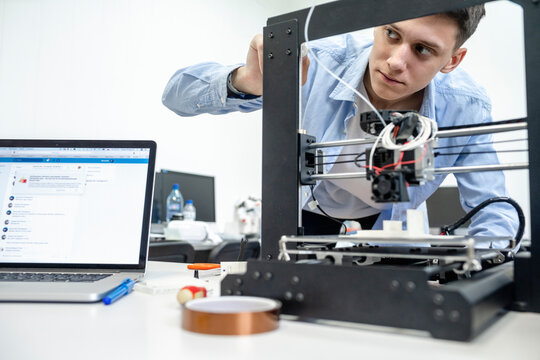 Student setting up 3D printer, using laptop