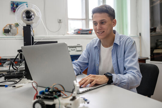 Student setting up 3D printer, using laptop