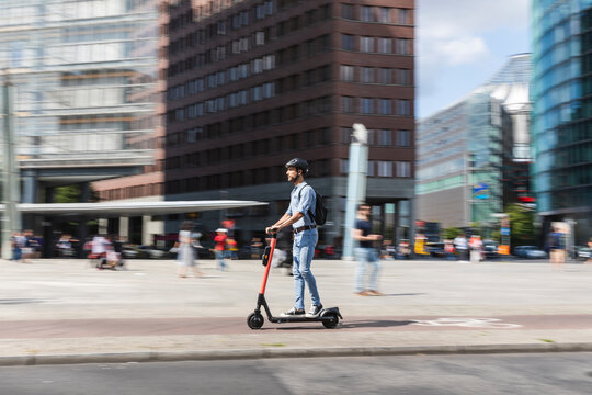 Businessman riding e-scooter on the pavement in the city, Berlin, Germany