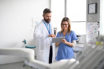 Obraz premium Doctor and female nurse looking at test results in tablet. Healthcare workers in Doctor's Office.
