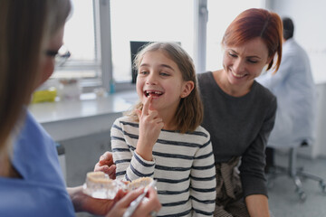 Girl showing her lost tooth to the dentist during a routine checkup at the dental clinic.
