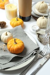 Rustic holiday table setup with plates, cutlery and autumn decorations