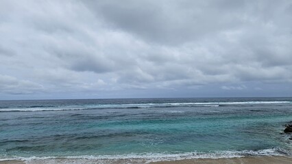 Scenic view of a calm ocean with gentle waves under a cloudy sky, creating a serene and tranquil atmosphere