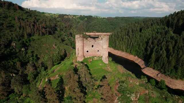 aerial shot going backward revealing Alleuze Castle and landscape on a partially cloudy day, Cantal departement, auvergne rhone alpes region, france