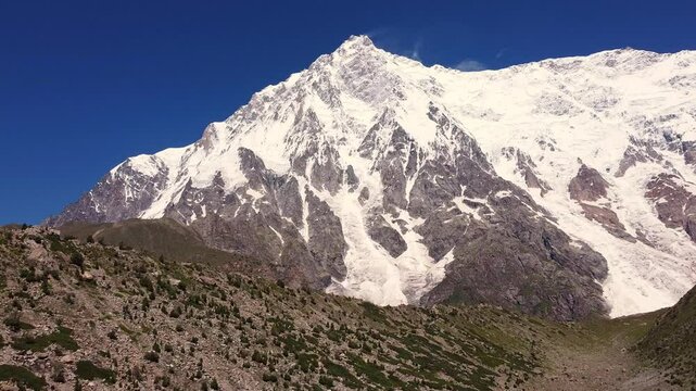 Nanga Parbat, the ninth highest mountain, towers over Rupal Valley in Gilgit Baltistan, Pakistan, draped in snow and ice. Aerial Rising Shot