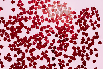 red metallic heart confetti on pink background. Minimalist holiday background for valentines
